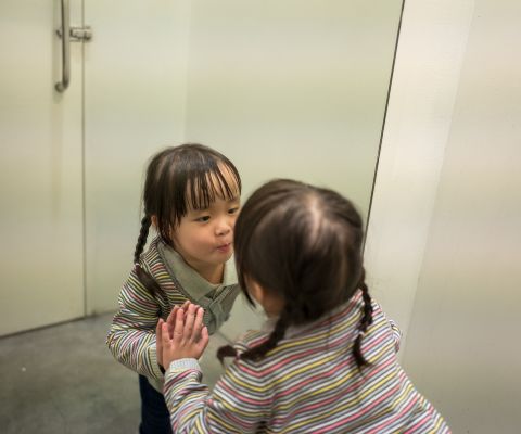 Kind betrachtet sich im Spiegel