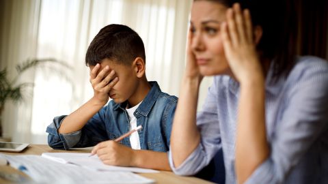 Madre e figlio stressati seduti a un tavolo davanti ai compiti a casa