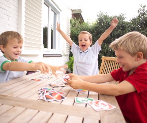 Vier Jungen am Tisch spielen Uno