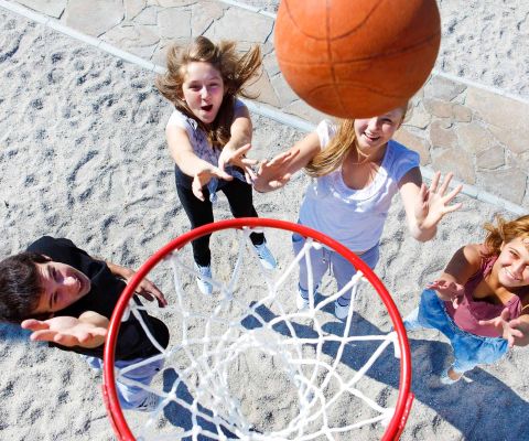 Des enfants jouent au basketball et lancent le ballon vers le panier 