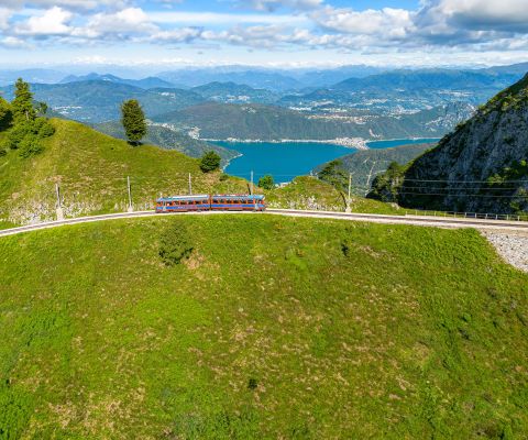 Die Zahnradbahn auf den Monte Generoso vor Alpen-Panorama und dem Luganersee