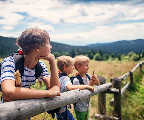 Tre bambini guardano in lontananza in un campo 