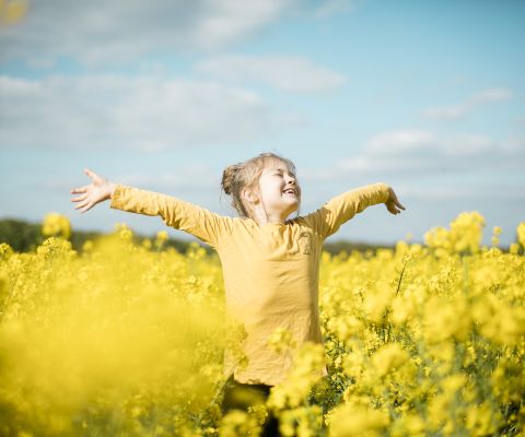 Una bambina si gode la primavera nel campo di colza
