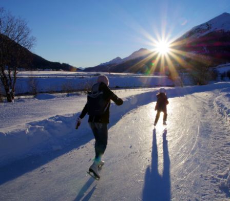 Frau mit kleinem Kind laufen Schlittschuh auf dem Eisweg Madulain 