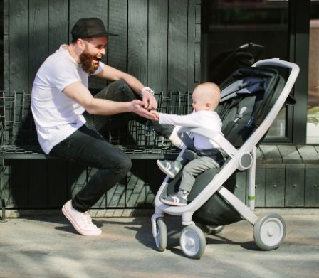 Un papà gioca col figlio sul passeggino
